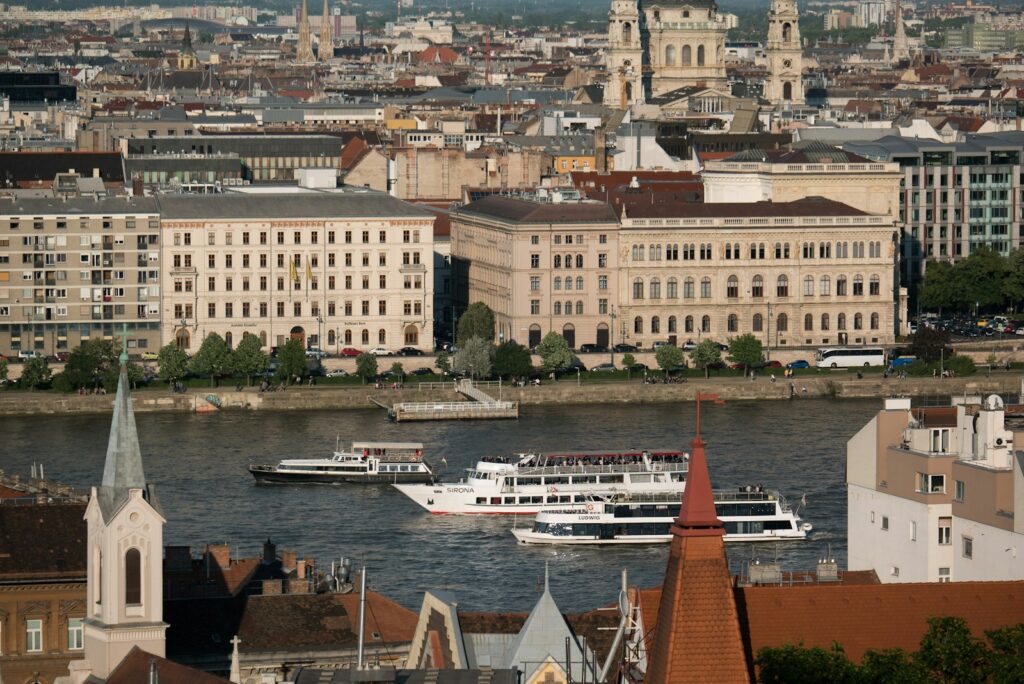 white and brown boat on water near brown concrete building during daytime